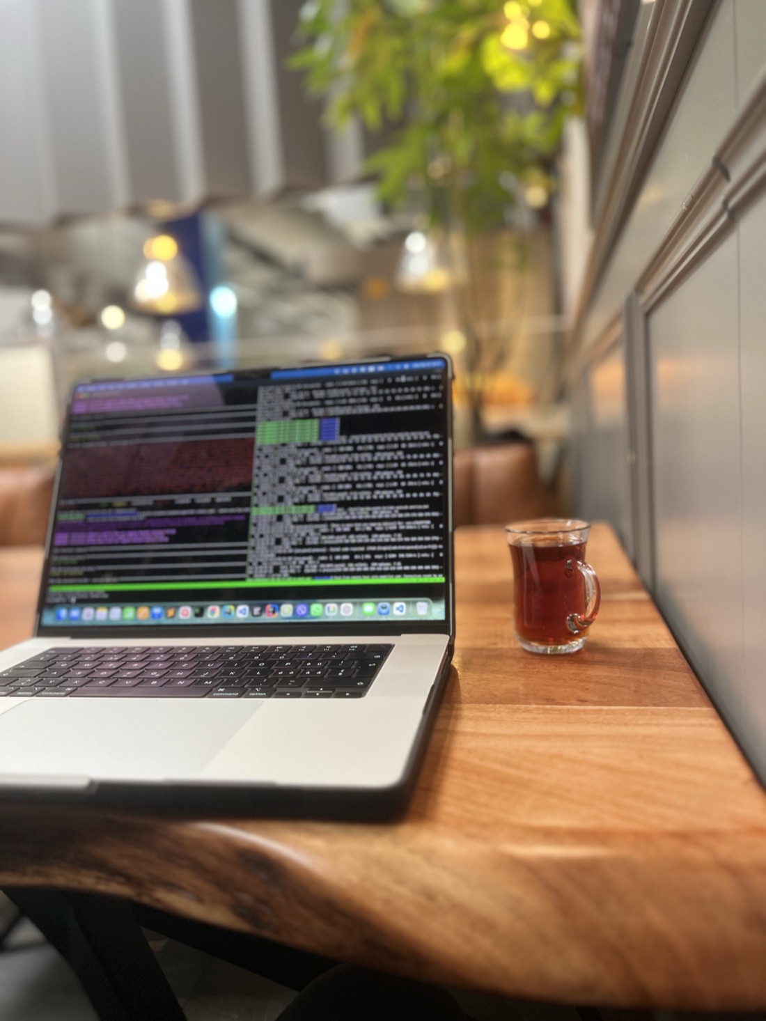 My workspace - a laptop showing code beside a glass of tea